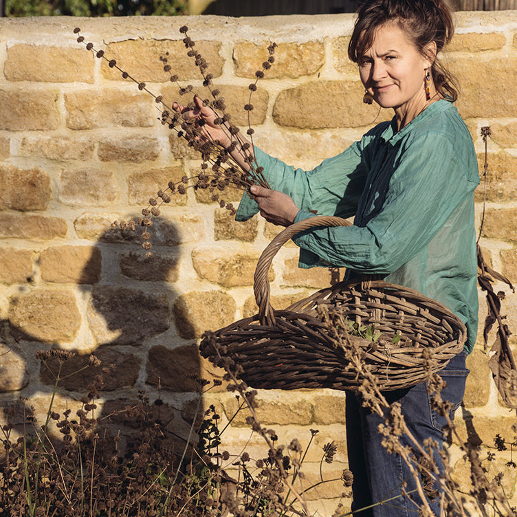 Zoe standing in front of a rustic stone wall in the sunlight.